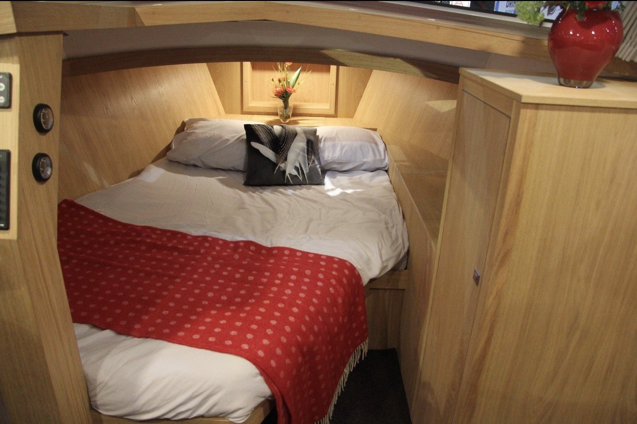 Slaaphut in licht eiken met een tweepersoonsbed met rode sprei, kastjes en een lamp
