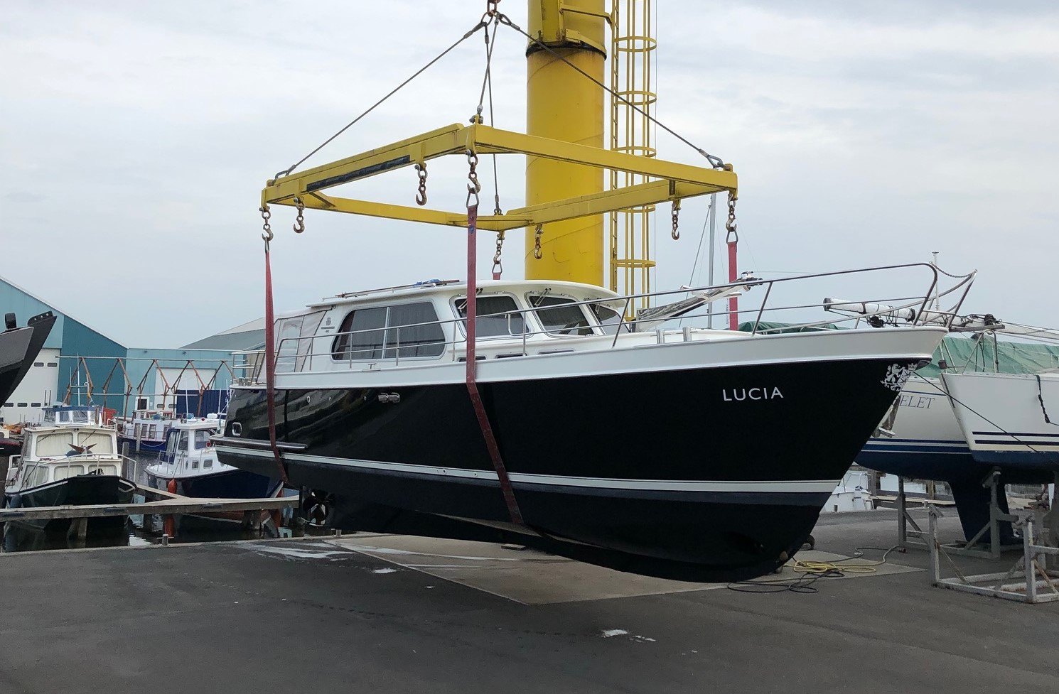Motorjacht in de hijsbanden van de gele portaalkraan